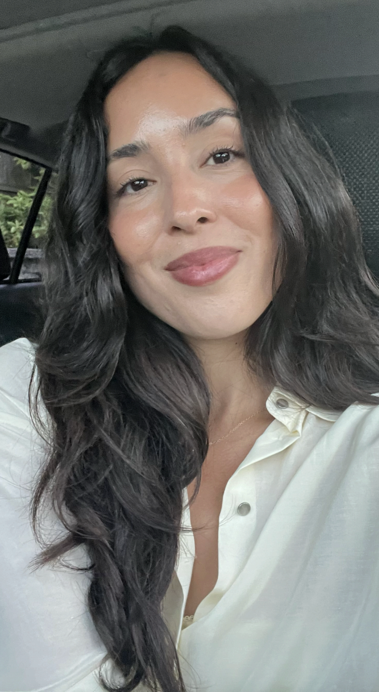 Marie smiling taking a selife with long dark hair in white shirt
