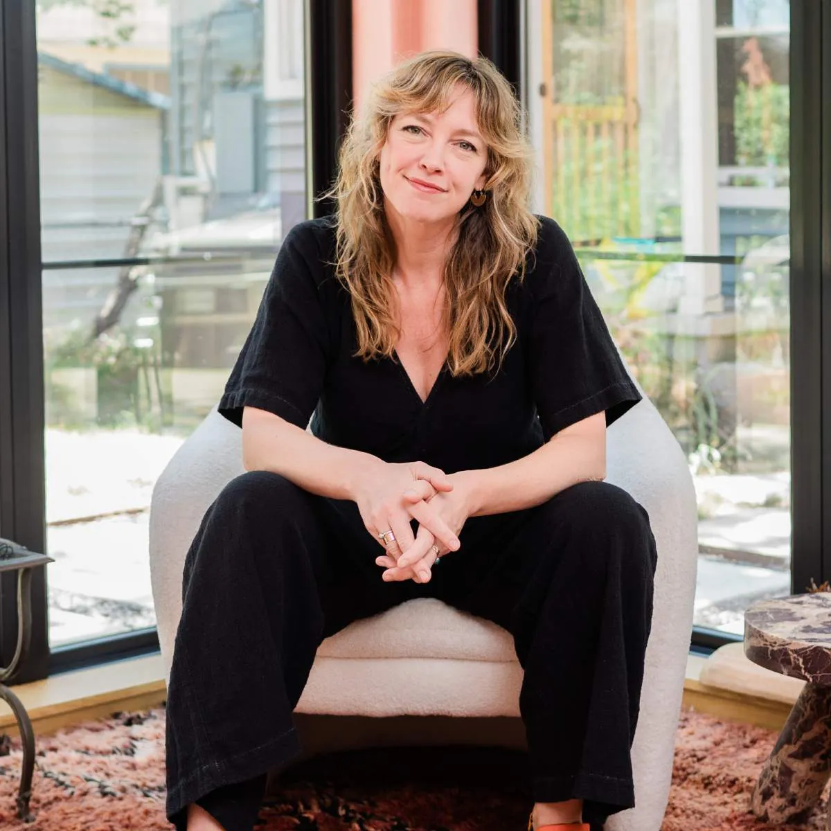 Portrait of Emily Van Eck sitting in a chair, wearing a black jumper