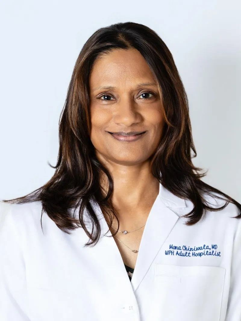 Portrait of Dr. Mona Chiniwala, smiling, in a white coat embroidered with her name